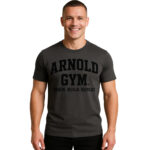 Fitness model wearing a charcoal Arnold Gym T-shirt showcasing the slogan Train. Build. Repeat., styled for gym and strength training.